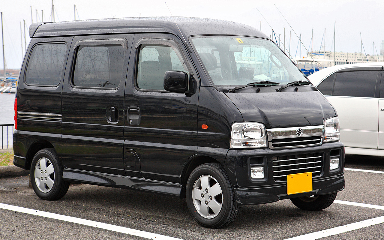 Black Suzuki Every kei van parked beside a marina